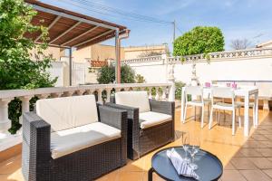 a patio with wicker chairs and a table with wine glasses at Maison La Coquette L' Escala in L'Escala