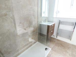 a bathroom with a shower with a tub and a sink at Craig Mawr in Benllech +15 photos