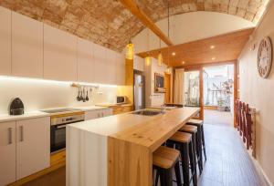 a kitchen with a large wooden island with stools at Sant Rafel House in Arenys de Mar
