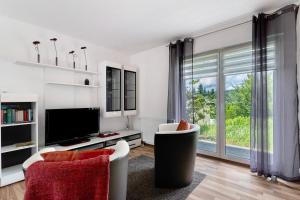 a living room with a tv and a large window at Ferienhaus Waldfee in Reutin