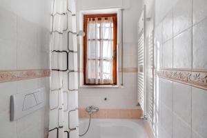 a white bathroom with a tub and a window at Casa di Lo in Laigueglia +12 photos