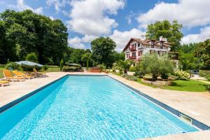 a swimming pool with a house in the background at Villa d’Exception, Piscine, Parc in Soustons