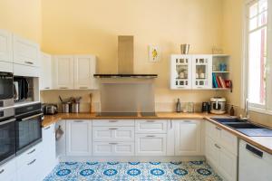 a kitchen with white cabinets and a tile floor at Villa d’Exception, Piscine, Parc in Soustons
