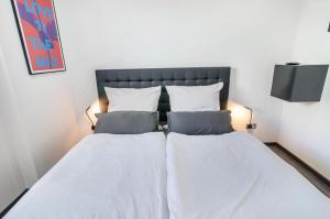 two beds in a bedroom with white sheets and pillows at Moin, die Ferienwohnung in Wilhelmshaven