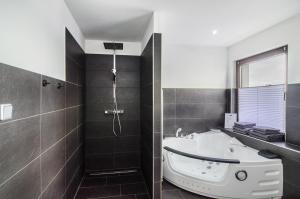 a bathroom with a bath tub and a shower at Moin, die Ferienwohnung in Wilhelmshaven +14 photos
