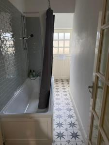 a bathroom with a tub and a tiled floor at Dickens HideAway in Hollington +12 photos