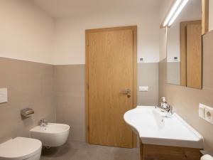a bathroom with a toilet and a sink and a door at Radlspitz Maurerhof in Valdurna +24 photos