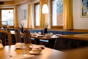 a restaurant with wooden tables and chairs and windows at Pension Waldheim Rooms in San Giacomo