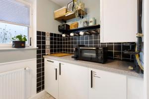 a kitchen with white cabinets and a microwave at Seeluft direkt am Wasser in Reichenau