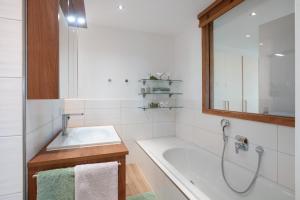 a white bathroom with a tub and a sink at Chalet Foret - Ferienwohnung in Todtnauberg +28 photos