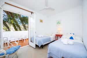 a bedroom with two beds and a balcony at Can Botana 7 in Cala de Sant Vicenc +25 photos