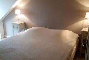 a white bed in a bedroom with two lights on at Gîte Joly in Corseul