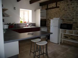 a kitchen with a black counter and two stools at Gîte Joly in Corseul
