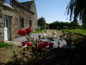 a garden with red roses and chairs and a building at Gîte Joly in Corseul