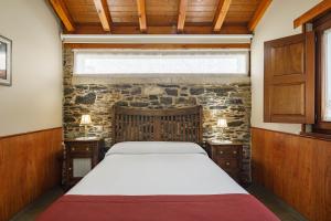 a bedroom with a bed and a stone wall at Camiño in Ordes