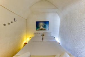 a bedroom with a white bed with a painting on the wall at Villa Blu La Cambusa in Castro di Lecce +19 photos