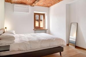 a white bedroom with a bed and a mirror at Vicolo 10 in Asti