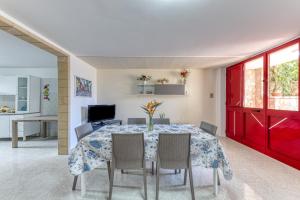 a dining room with a table with chairs and a red door at Pilella in Alliste