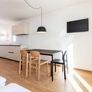 a kitchen and dining room with a black table and chairs at Hus Appartement - Nr. 4 in Valdaora