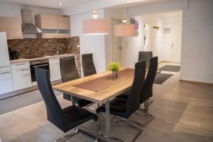 a kitchen with a wooden table and black chairs at Villa Nordhang - Apartment 04 in Winterberg
