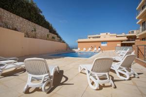 a group of lawn chairs and a swimming pool at Praia Areia Branca in Lourinhã