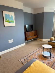 a living room with a blue wall and a tv at Dickens HideAway in Hollington