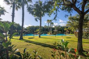 a park with palm trees and a swimming pool at Villa Rompido in Cartaya
