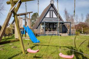 a swing set in a yard with a house at Sonnenschein Am Meer in Butjadingen