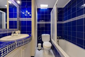 a blue tiled bathroom with a toilet and a sink at Casita en Cala Llonga in Cala Llonga +17 photos