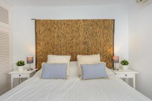 a bedroom with a bed with two blue pillows at Casita en Cala Llonga in Cala Llonga