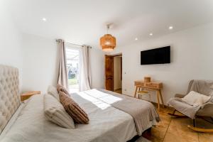 a bedroom with a bed and a tv and a chair at Lila Mas in Camaret-sur-Aigues +23 photos