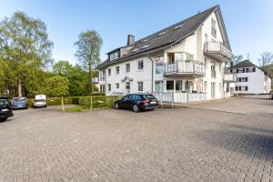 a large white house with cars parked in a parking lot at Fewo Willingenliebe Meinecardplus in Willingen