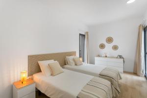 two beds in a white bedroom with a lamp on a table at Yucas Villa 14 in San Bartolomé +20 photos