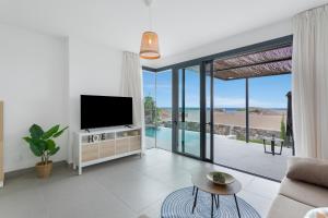a living room with a tv and sliding glass doors at Yucas Villa 14 in San Bartolomé
