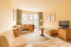 a hotel room with a couch and a desk and a television at Hotel Am Weberplatz in Dresden