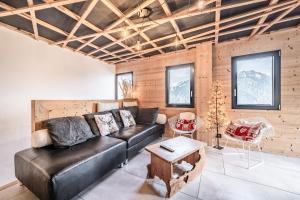 a living room with a leather couch and a table at Martonne Terrasse chatel Roca in Châtel