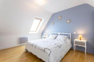 a bedroom with a white bed and a blue wall at Maisonette face à la mer in Trégunc