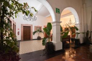 a hallway with a chandelier in a building with plants at Hotel Catedral in Cuernavaca