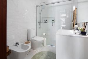 a white bathroom with a shower and a toilet and a sink at Ocean City View Loft in Ponta Delgada +14 photos