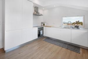 a white kitchen with white cabinets and a window at Ocean City View Loft in Ponta Delgada