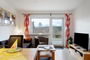 a living room with a couch and a tv and a window at Haus Intlekofer in Lenzkirch