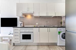a white kitchen with a sink and a dishwasher at Barlovento Apartment in Playa Honda