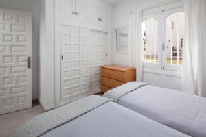 a white bedroom with two beds and a door at Bright spacious 1 bed apartment in Nerja