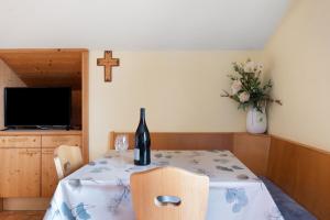 a dining room table with a bottle of wine and a cross at Haus Prossliner in Tesimo
