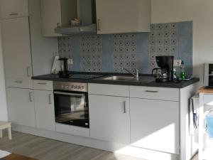 a white kitchen with a sink and a stove at Ferienwohnung Unter Reet in Risum-Lindholm