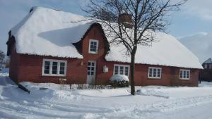 a red brick house with a snow covered roof at Ferienwohnung Unter Reet in Risum-Lindholm