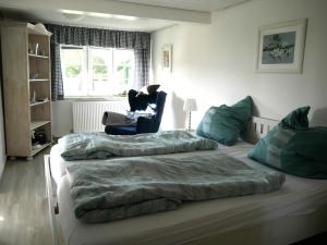 a bedroom with two beds and a chair at Ferienwohnung Unter Reet in Risum-Lindholm +3 photos