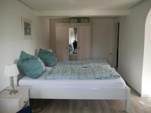 a white bed with blue pillows in a bedroom at Ferienwohnung Unter Reet in Risum-Lindholm