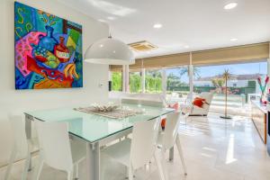 a dining room with a glass table and white chairs at Traviata in Cap Blanc
