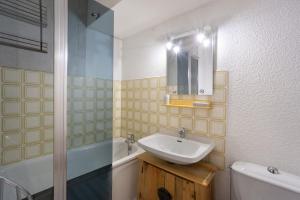 a bathroom with a sink and a mirror and a tub at Les Airelles 32 in Villarodin-Bourget